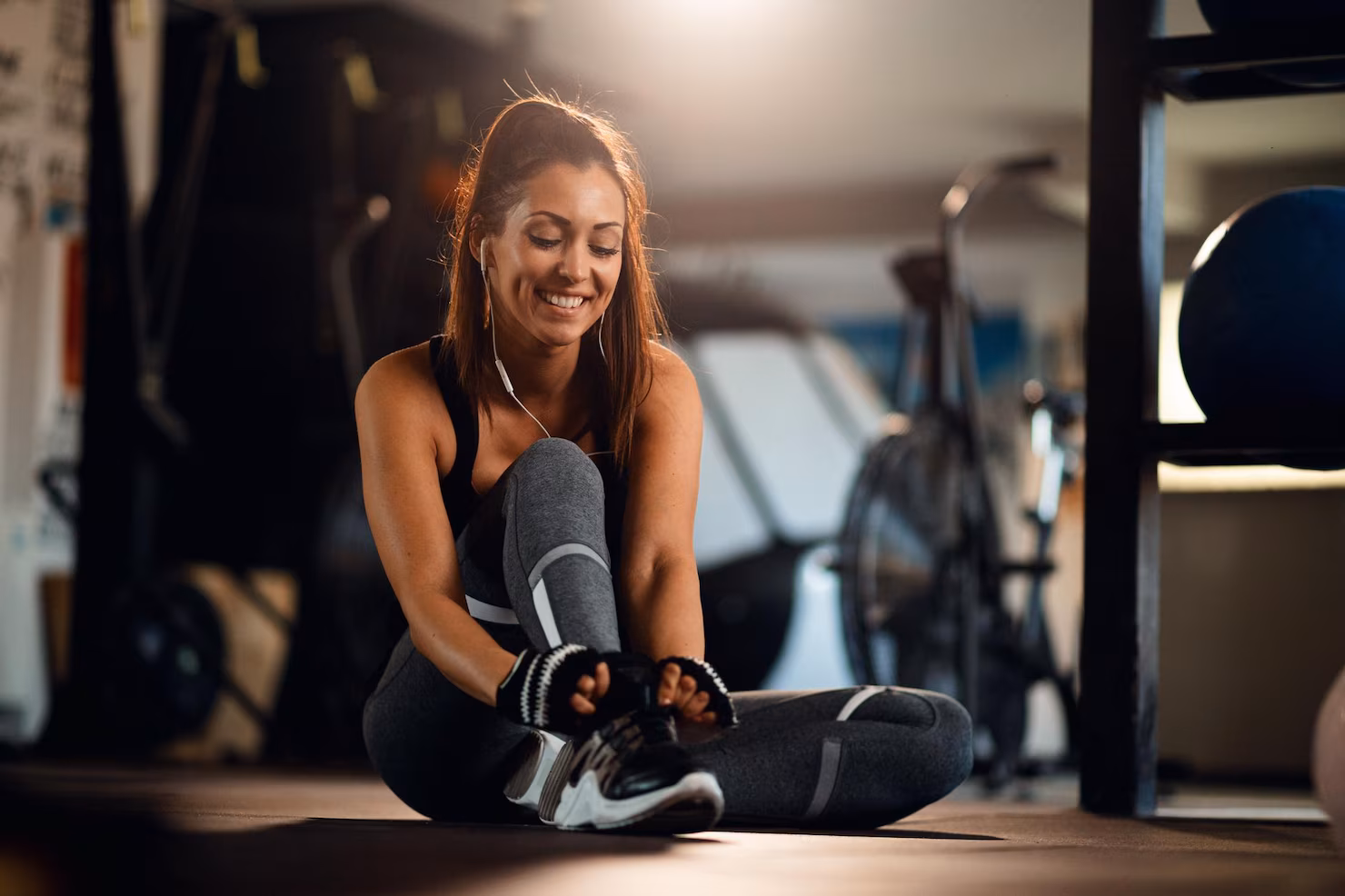 joven-deportista-feliz-preparandose-hacer-ejercicio-atarse-cordones-zapatos-gimnasio_637285-470